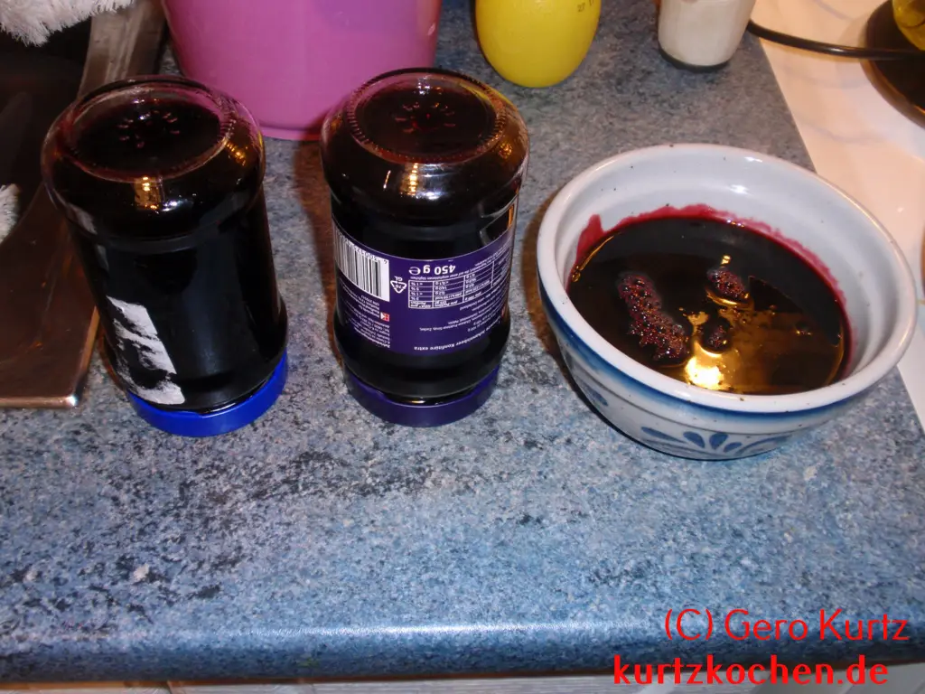 zwei umgedrehte Marmeladengläser und eine Schale mit Holunderbeergelee