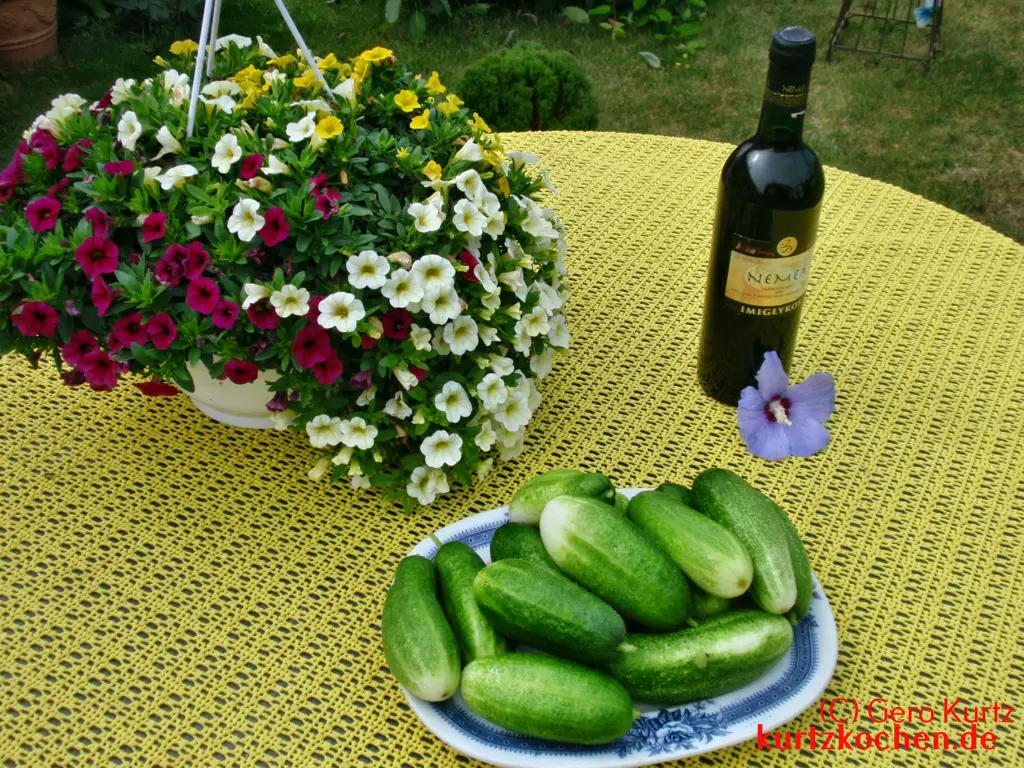 Teller mit Gurken auf einem Tisch mit Blumen und Wein