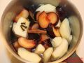 Apfel und Pflaumenstücke in einem Kochtopf mit Wasser