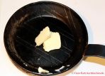 Rezept für schnellen Eierkuchen - Fett in einer Pfanne aus Gusseisen